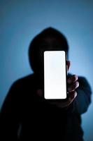 Indonesië, 21122021 - een silhouet van een man met hoodie houdt een telefoon vast foto