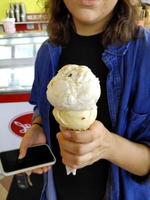 ijs smaak vanille bevroren dessert patroon in wafel kegel hand vasthouden op tafel. foto