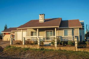 cambara do sul, brazilië - 16 juli 2019. charmant modern herenhuis met hek en tuin bij zonsondergang, in een onverharde straat van cambara do sul. een klein stadje met verbazingwekkende natuurlijke toeristische attracties. foto