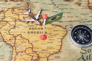 vlag van brazilië, kompas en vliegtuig op de wereldkaart. foto
