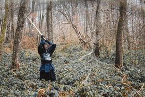 man die kendo beoefent met shinai bamboezwaard op bosachtergrond foto