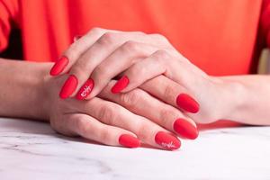 rode matte manicure op vrouwelijke handen voor Valentijnsdag foto
