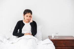 de zieke vrouw had hoofdpijn en de handen raakten haar hoofd op het bed. foto