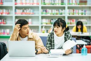 vrouwen lezen boeken en mannen gebruiken laptops om boeken te zoeken in bibliotheken. foto