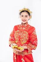 vrouw draagt cheongsam-pak geeft goud aan haar familie voor geluk in chinees nieuwjaar foto