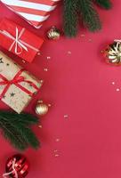 kerst compositie. dozen als geschenk op tak dennenboom op rode backgraund. bovenaanzicht, kopieer ruimte