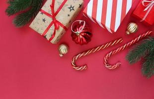 kerst compositie. dozen als geschenk op tak dennenboom op rode backgraund. bovenaanzicht, kopieer ruimte