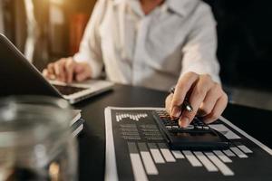 hand man doet financiën en op bureau over kosten op kantoor. foto