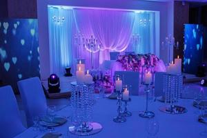 luxe trouwtafel met decor, met zilveren kandelaars, kaarsen en bloemen in blauw licht. selectieve foto