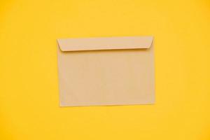 kraftpapier envelop op een gele achtergrond. perfect voor uitnodigingen, kaarten, berichtdecoraties foto
