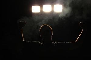 de kampioen - silhouet van een gelukkige man die zijn overwinning viert. mist die om hem heen zweeft. foto