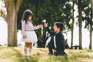 knielende jongen die een huwelijksaanzoek doet met een bloem - een jongen die een huwelijksaanzoek doet met een romantisch gebaar zijn vriendin foto