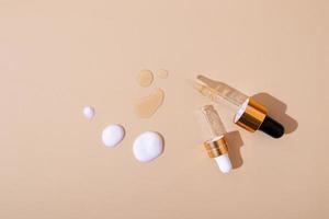 druppelaar en druppels olie of serum, druppels nv-crème op beige oppervlak - cosmetica en spa-producten bovenaanzicht foto
