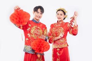 man en vrouw dragen cheongsam-pak vieren Chinees nieuwjaar met rode lamp en voetzoeker foto
