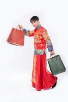man draagt cheongsam-pak glimlach met papieren zak van winkelen in chinees nieuwjaar foto