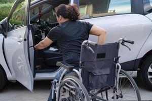 aziatische vrouw vouwt en tilt rolstoel op in haar auto. toegankelijkheidsconcept. foto