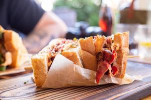 een krokant broodje met vlees en andere toppings liggend op de tafel van een restaurant. foto