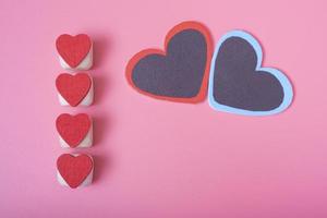 vier rode harten verticaal op een rij aan de linkerkant, roze achtergrond. foto