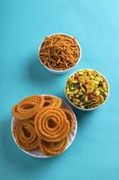 Indiase snack chakli, chakali of murukku en besan gram meel sev en chivada of chiwada op blauwe achtergrond. diwali eten foto