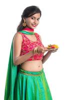 mooi Indisch jong meisje dat pooja thali vasthoudt of aanbidding uitvoert op een witte achtergrond foto