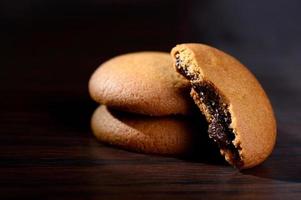 koekjes gevuld met chocoladeroom. chocolade crème koekjes. bruine chocoladekoekjes met roomvulling op zwarte achtergrond. foto