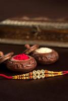 Indiase festival raksha bandhan achtergrond met een elegante rakhi, rijstkorrels en kumkum. een traditionele Indiase polsband die een symbool is van liefde tussen broers en zussen. foto