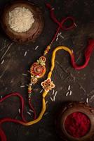 raksha bandhan achtergrond met een elegante rakhi, rijstkorrels en kumkum. een traditionele Indiase polsband die een symbool is van liefde tussen broers en zussen. foto