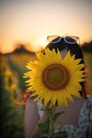 gelukkig vrolijk Aziatisch meisje met zonnebloem genietend van de natuur en glimlach op de zomer in zonnebloemveld. foto