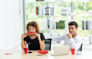 twee kantoormedewerkers drinken water en eten watermeloen foto