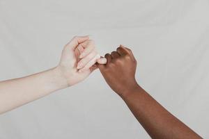close-up eerlijke donkere vrouwen handen maken pinkie belofte tegen grijze achtergrond