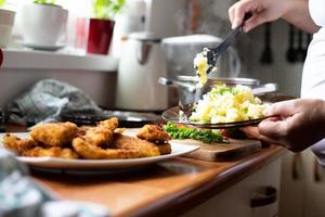 voorbereiding van een traditioneel diner in de keuken van het huis. gepaneerde kip met aardappelen. foto