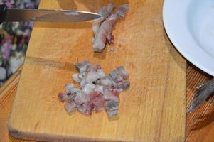 haring snijden met een mes op een keukenplank foto