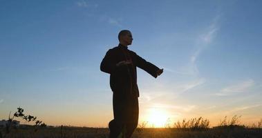 silhouet van jonge mannelijke kungfu-jager die alleen in de velden oefent tijdens zonsondergang foto