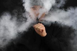 mannen roken een elektronische sigaret op de donkere achtergrond. selectieve focus foto