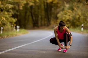 jonge vrouw heeft een pauze tijdens de training in het herfstbos foto