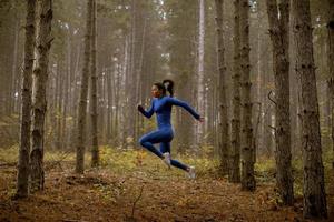 jonge vrouw die hoogspringt op het bospad in de herfst foto