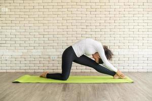 latijnse vrouw die yoga beoefent op mat foto