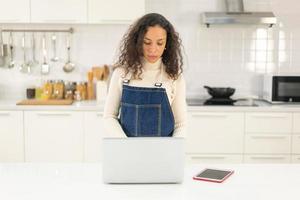 Latijnse vrouw zoekt recept voor koken in de keuken foto