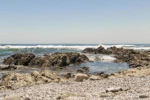 sterke golven, stenen zeekliffen, zeepunt promenade kaapstad. foto