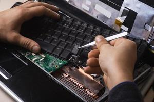 tovenaar repareert laptop met gereedschap en handen foto