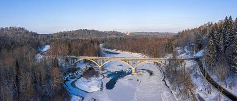 winterseizoen luchtfoto van boven naar beneden uitzicht op een brug met een rechte lijnweg over de rivier
