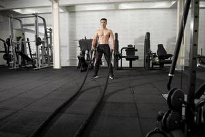 Aziatische atletische man met touw doen oefening in fitness gym foto