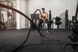 Aziatische atletische man met touw doen oefening in fitness gym foto