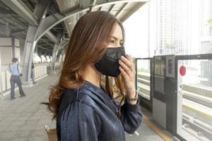 mooie vrouw die een antistofmasker draagt, beschermt luchtvervuiling en pm 2.5 op straatstad foto