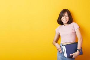 mooie Aziatische vrouw universiteitsstudent gelukkig op gele achtergrond foto