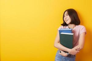 mooie Aziatische vrouw universiteitsstudent gelukkig op gele achtergrond foto