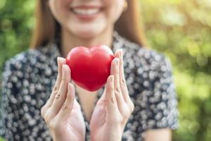 vrouwenhand houdt rood hart, liefde en gezondheidszorgconcept vast foto