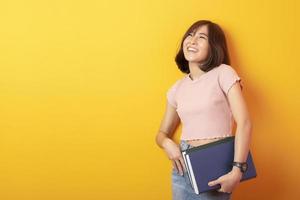 mooie Aziatische vrouw universiteitsstudent gelukkig op gele achtergrond foto