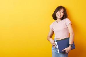 mooie Aziatische vrouw universiteitsstudent gelukkig op gele achtergrond foto