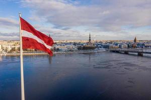 panoramisch uitzicht over de stad Riga met een grote Letse vlag aan de rivier de Daugava. Letse geest. foto